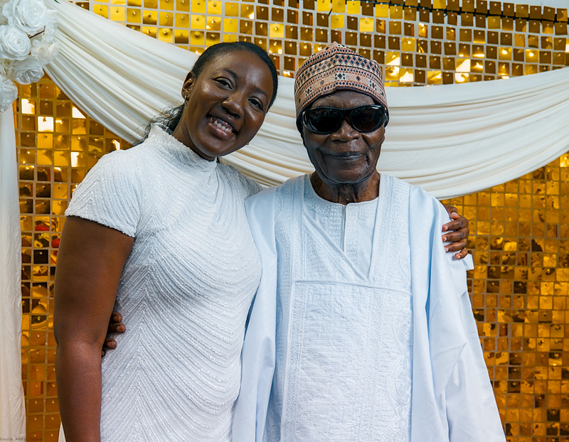 A guest leans in to the celebrant at the gold photo wall
