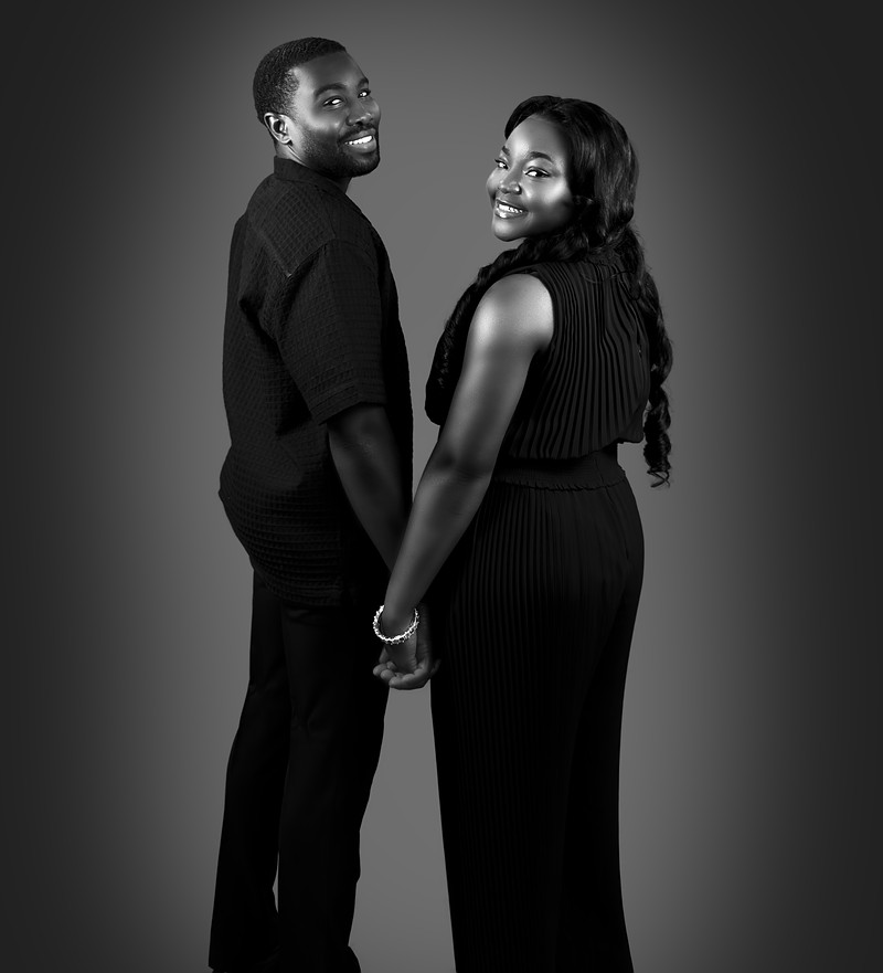 Black and white full-length portrait of the couple holding hands and looking back over their shoulders
