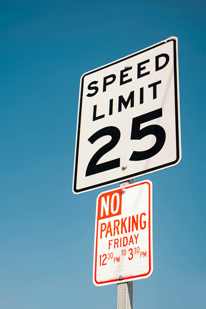A speed limit sign and a no parking sign against a deep blue sky