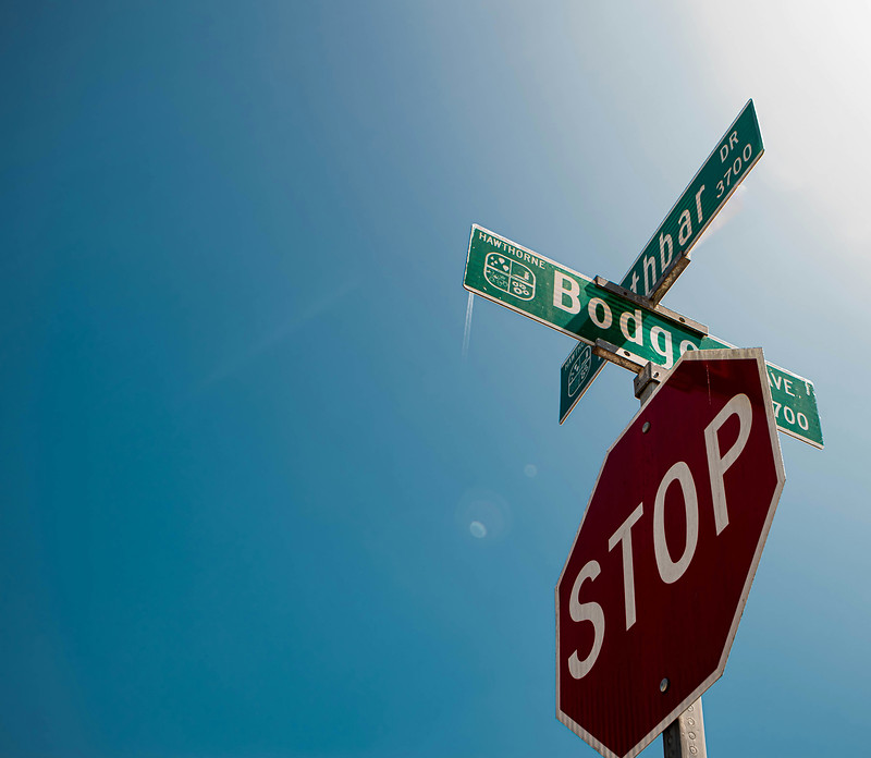 A stop sign and street name signs against a graded blue sky