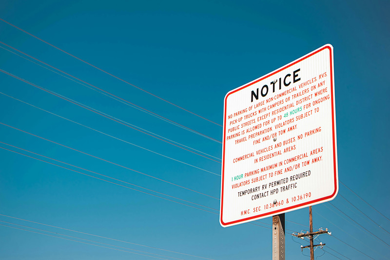 A parking notice sign beneath overhead power lines